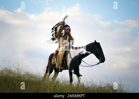 cowboy sur son cheval pendant la course des chevaux et, en arrière-plan, un groupe de six cowboys et cowgirls supervisant la course des chevaux Banque D'Images