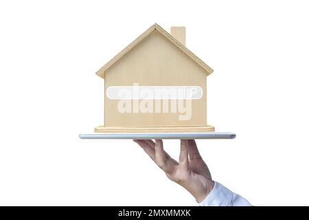 Une main tenant une tablette et une maison modèle en bois avec une icône de barre de recherche. Banque D'Images