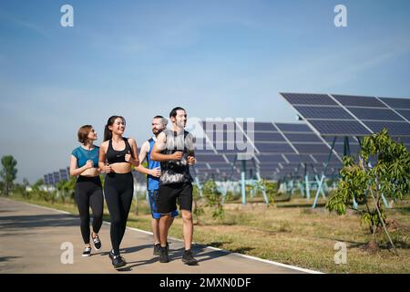 Active style de vie jeune homme coureur courir par panneaux solaires ferme à l'extérieur arrière-plan d'été. Concept de durabilité Banque D'Images