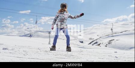 Prise de vue en longueur d'une femelle avec des lunettes et un casque, en snowboard sur une montagne enneigée Banque D'Images