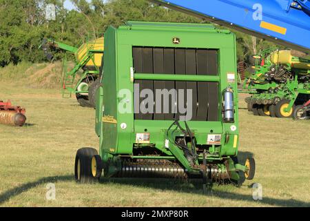 Ramasseuse-presse John Deere chez un concessionnaire avec herbe verte et arbres Banque D'Images