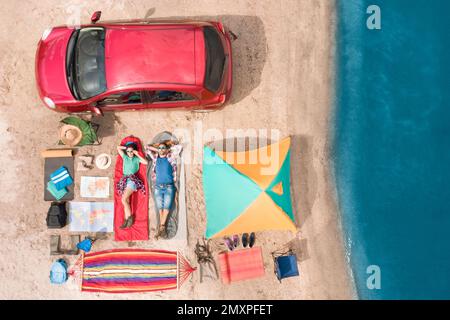 Couple avec équipement de camping près de la voiture sur le sable, vue aérienne. Voyage d'été Banque D'Images