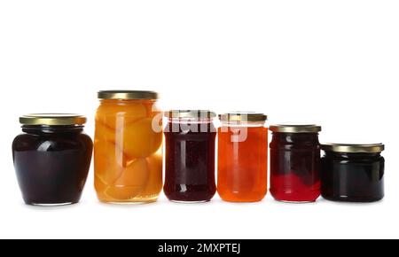 Pots en verre avec différents fruits marinés et confitures sur fond blanc Banque D'Images