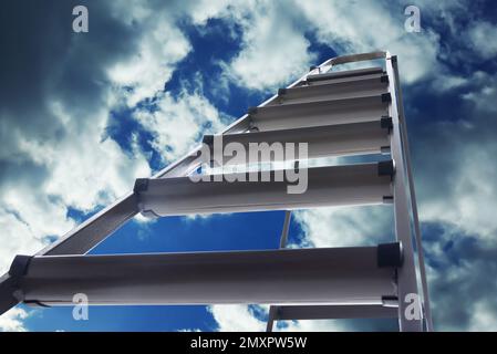 Escabeau en métal contre ciel bleu avec nuages, vue en angle bas Banque D'Images