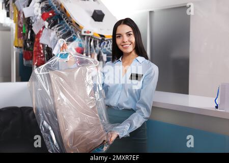 Femme travaillant avec des vêtements dans des nettoyeurs à sec modernes Banque D'Images