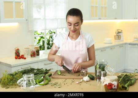 Femme coupant le concombre à la table dans la cuisine. Préparation des cornichons Banque D'Images