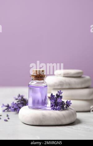 Pierres, bouteille d'huile essentielle et fleurs de lavande sur une table en marbre Banque D'Images