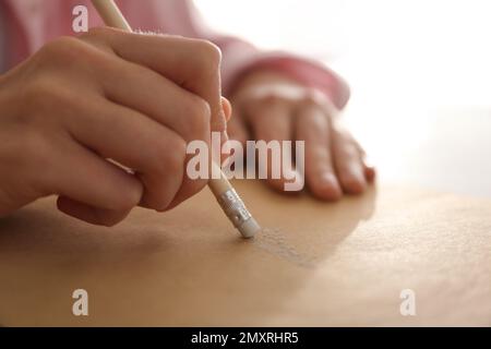 Femme corrigeant l'image sur le papier avec la gomme du crayon, gros plan Banque D'Images