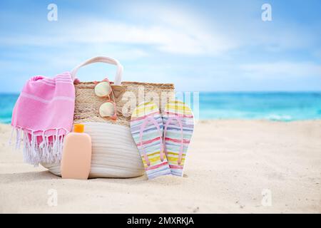 Différents objets de plage élégants sur le sable près de la mer. Espace pour le texte Banque D'Images