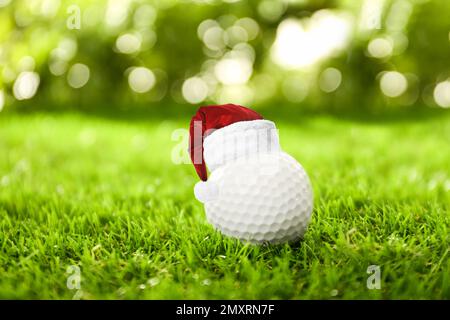 Balle de golf avec petit chapeau de père Noël sur le green Banque D'Images