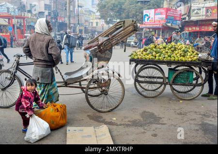 INDE. UTTARPRADESH. VARANASI. (BENARES) FILLE AIDE DAD À TRANSPORTER DES MARCHANDISES DEVANT SON POUSSE-POUSSE Banque D'Images