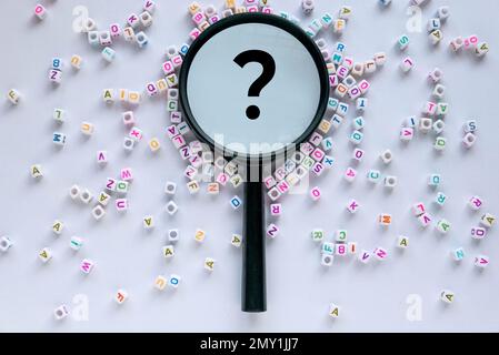 Concept de questions et réponses. Perles d'alphabet avec loupe avec symbole d'interrogation sur fond blanc. Banque D'Images