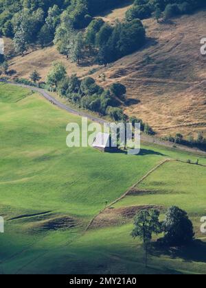 Route de campagne sinueuse et ferme sur une colline verte Banque D'Images