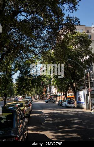 Vue sur la rue Catete pleine d'arbres et de voitures garées autour sous l'ombre des arbres, près de la rue Santo Amaro sous le matin été ensoleillé ciel bleu clair. Banque D'Images