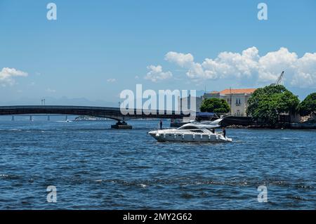 Un hors-bord blanc naviguant sur les eaux de la baie de Guanabara dans le quartier du Centro avec le pont Arnaldo Luz à l'arrière-midi d'été ensoleillé ciel clair Banque D'Images