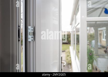 Mise au point peu profonde d'une nouvelle porte latérale haute sécurité installée dans un garage. Le jardin arrière et la véranda sont visibles. Banque D'Images