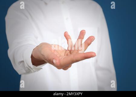 Femme montrant quelque chose sur fond bleu, se concentrer sur la main Banque D'Images