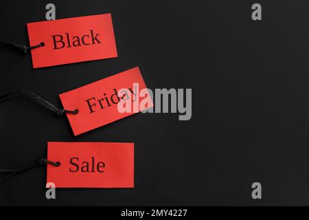 Étiquettes rouges avec mots NOIR SOLDE VENDREDI sur fond sombre, plat. Espace pour le texte Banque D'Images