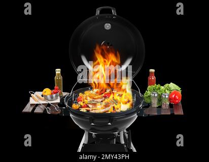 Barbecue moderne flamboyant avec des plats savoureux sur fond noir Banque D'Images