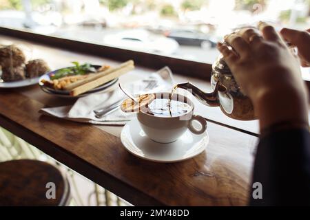 le thé noir est versé dans la tasse avec de l'orange sur la table du petit déjeuner à l'extérieur. Concept sain photo de haute qualité Banque D'Images