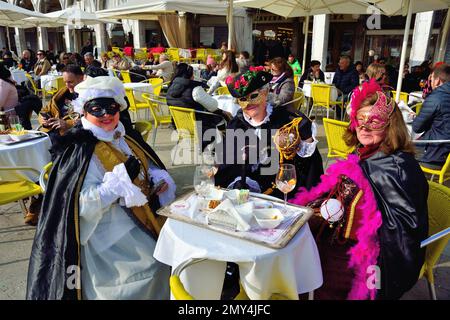 4 février 2023. Premier jour du carnaval de Venise. Trois masques prenant un verre sur la Piazza San Marco. Banque D'Images