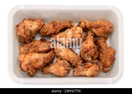 Ailes de poulet frites précuites dans un plateau en plastique pour la vente au supermarché , isolées sur blanc avec un chemin de coupure Banque D'Images