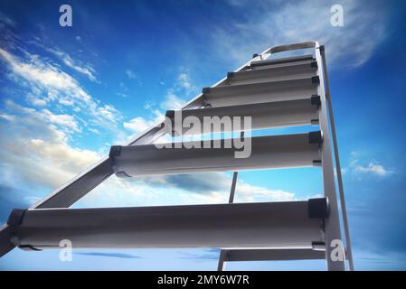 Escabeau en métal contre ciel bleu avec nuages, vue en angle bas Banque D'Images