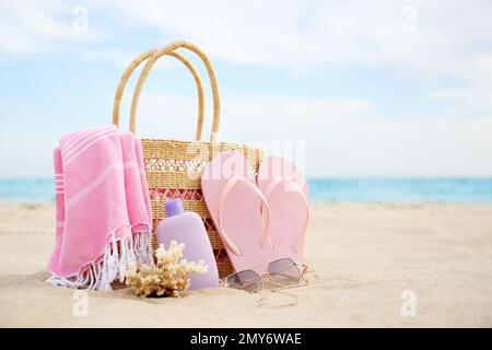 Différents objets de plage élégants et corail sur le sable près de la mer. Espace pour le texte Banque D'Images