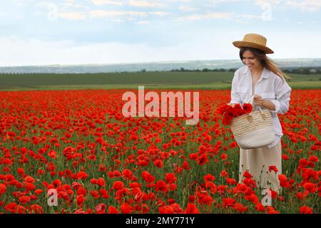 Femme tenant un sac à main avec des fleurs de pavot dans un beau champ Banque D'Images