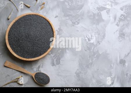 Tête de pavot séchée, bol et cuillère avec graines sur table grise, plat. Espace pour le texte Banque D'Images