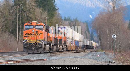 Baring, WA, Etats-Unis - 1 février 2023 ; train de fret à conteneurs BNSF avec plusieurs locomotives en hiver dans les montagnes Cascade en WA Banque D'Images