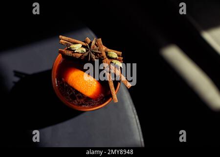 Thé à l'orange avec cannelle et cardamome en grands verres, bâtonnets d'orange et de cannelle sur fond sombre. Photo de haute qualité Banque D'Images
