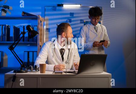 Les médecins travaillant la nuit à l'hôpital, collègues thérapeutes sur le lieu de travail discutant des diagnostics et des tests des patients Banque D'Images
