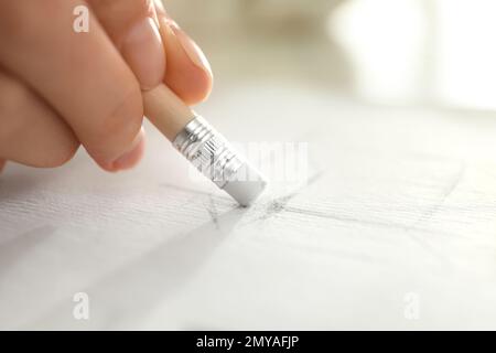 Femme corrigeant l'image sur le papier avec la gomme du crayon, gros plan Banque D'Images