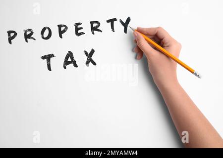 Femme écrivant l'impôt foncier sur fond blanc, gros plan Banque D'Images