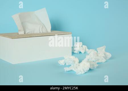 Papier mouchoirs et support utilisés sur fond bleu clair Banque D'Images