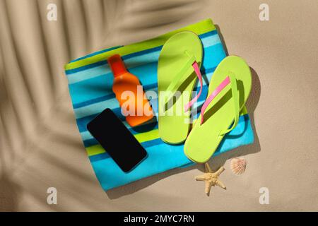 Composition Flat Lay avec smartphone et objets de plage sur le sable Banque D'Images