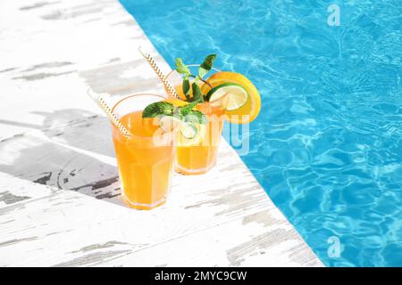 Cocktail rafraîchissant dans des verres près de la piscine extérieure le jour ensoleillé Banque D'Images