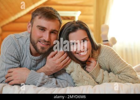 Jeune couple portant des chandails chauds sur le lit à la maison Banque D'Images