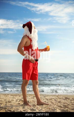 Santa Claus avec cocktail sur la plage. Vacances de Noël Banque D'Images