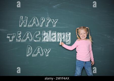 Jolie petite fille pointant sur un tableau noir avec texte Happy Teacher's Day Banque D'Images