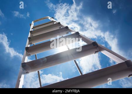 Escabeau en métal contre ciel bleu avec nuages, vue en angle bas Banque D'Images