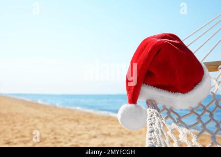 Hamac en corde avec chapeau de père Noël sur la plage, gros plan. Vacances de Noël Banque D'Images