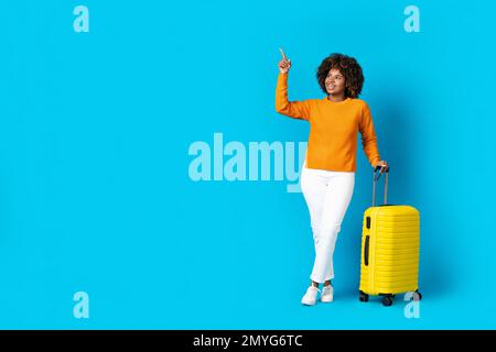 Jeune fille noire gaie voyageur pointant vers l'espace de copie Banque D'Images