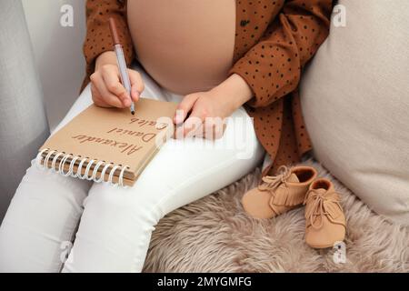 Femme enceinte écrivant la liste des noms de bébé, gros plan Banque D'Images