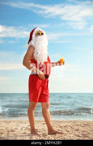 Santa Claus avec cocktail sur la plage. Vacances de Noël Banque D'Images