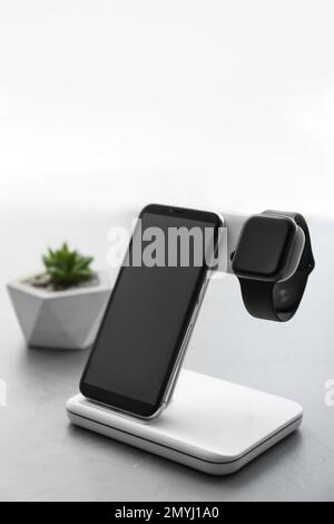 Élégante montre intelligente et recharge de téléphone avec clavier sans fil sur une table grise Banque D'Images