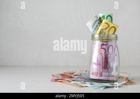 Pot en verre plein d'argent sur table lumineuse. Espace pour le texte Banque D'Images