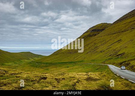 Route étroite au col du village de Gjogv avec voiture dans la vallée herbeuse sur l'île d'Eysturoy dans les îles Féroé Banque D'Images