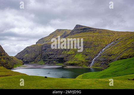 Pollurin Bay et Waterfall près de la ville de Saksun sur l'île de Streymoy, îles Féroé à marée basse par une journée nuageuse avec des moutons en pâturage Banque D'Images